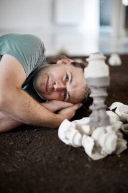 ceramic artist laying on the floor between his ceramics
